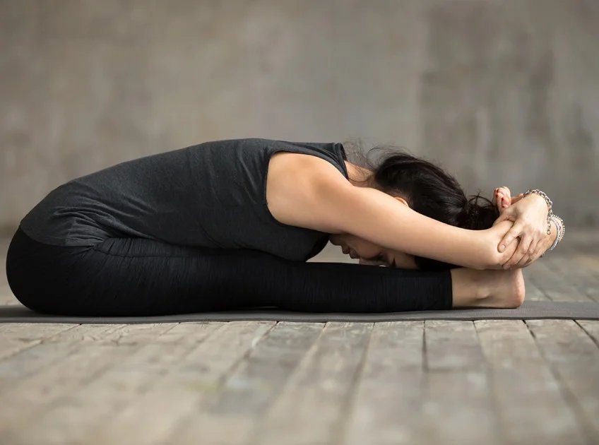 Yoga practitioner in seated forward fold pose demonstrating flexibility and focus