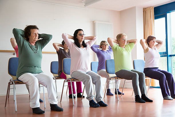 Chair yoga class – group of seniors performing seated stretches with hands behind head